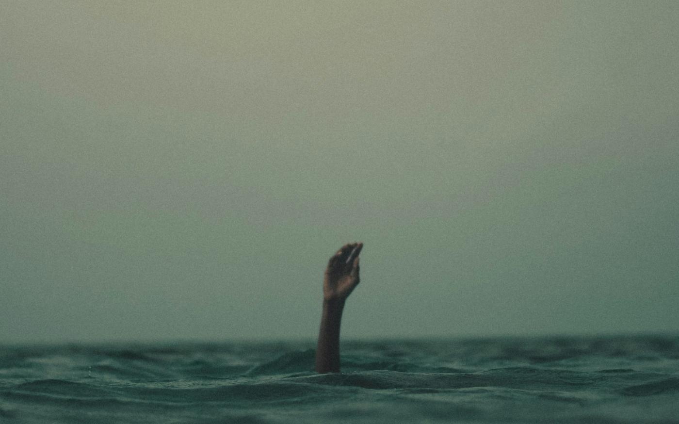 person with hand above water by Mishal Ibrahim courtesy of Unsplash.