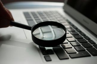 magnifying glass near gray laptop computer by Agence Olloweb courtesy of Unsplash.