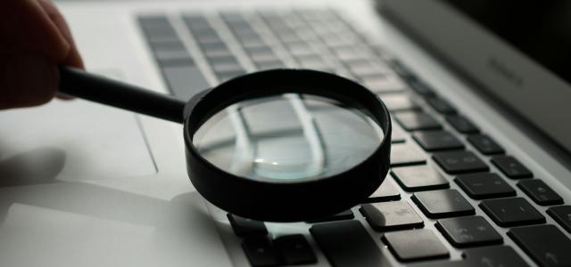 magnifying glass near gray laptop computer by Agence Olloweb courtesy of Unsplash.